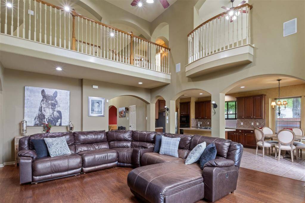 Soaring ceilings and graceful archways define the grand living area, offering both scale and warmth for everyday comfort and effortless entertaining. Overlooking the kitchen and breakfast room, this open-concept design invites connection and flow throughout the heart of the home.