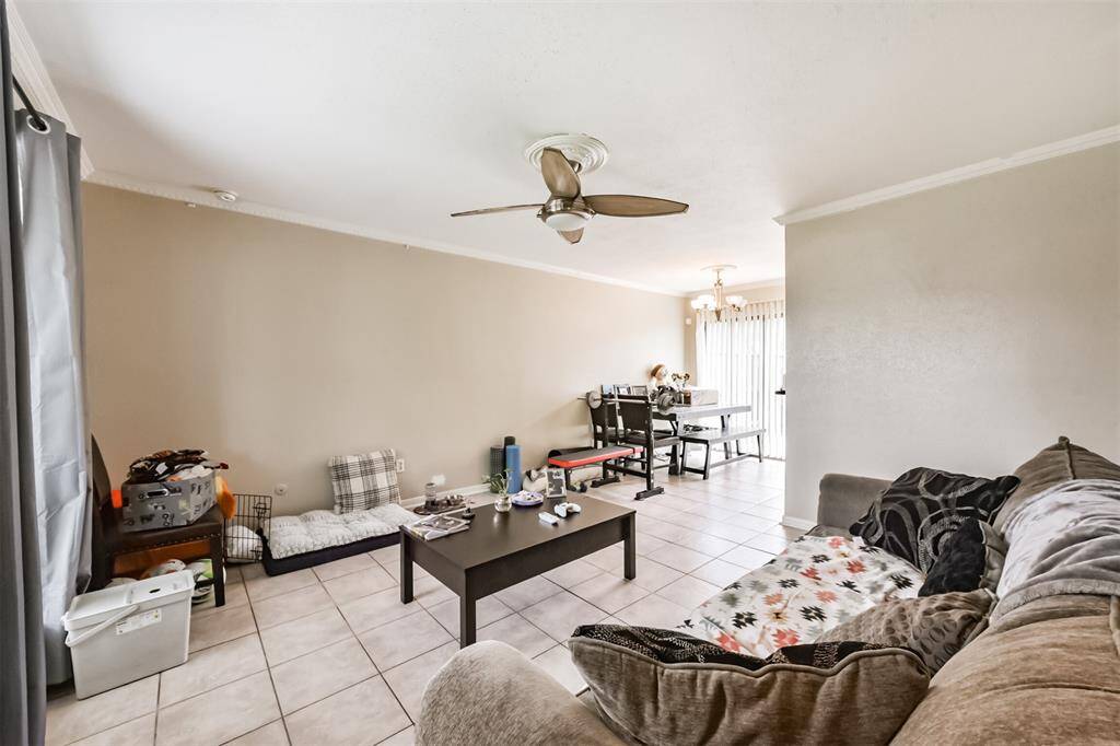 The living room has crown molding, tile floors and a ceiling fan.