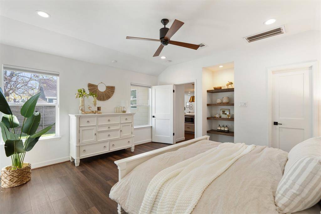 The primary suite boasts raised ceilings, abundant natural light from the windows, and stylish shelving.