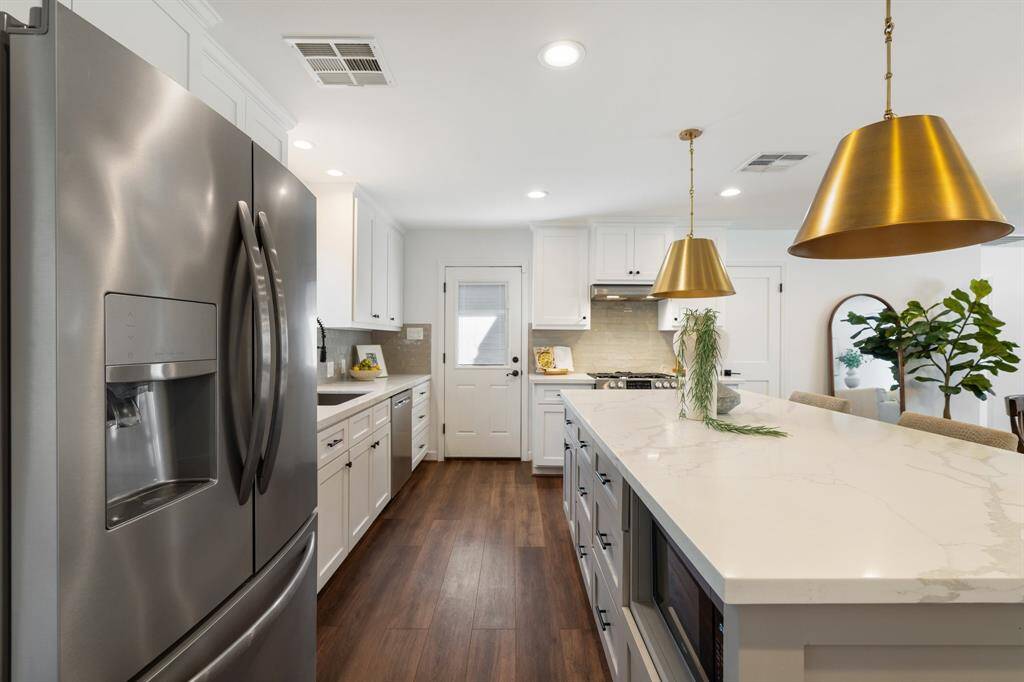 The updated kitchen is complete with quartz countertops, ample custom cabinetry, a walk-in pantry, and subway tile backsplash.
