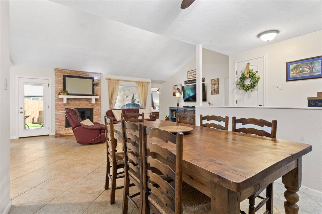 This inviting living space features an open layout with a cozy brick fireplace and ample natural light from the patio door and large picture windows. Perfect for family gatherings and entertaining.