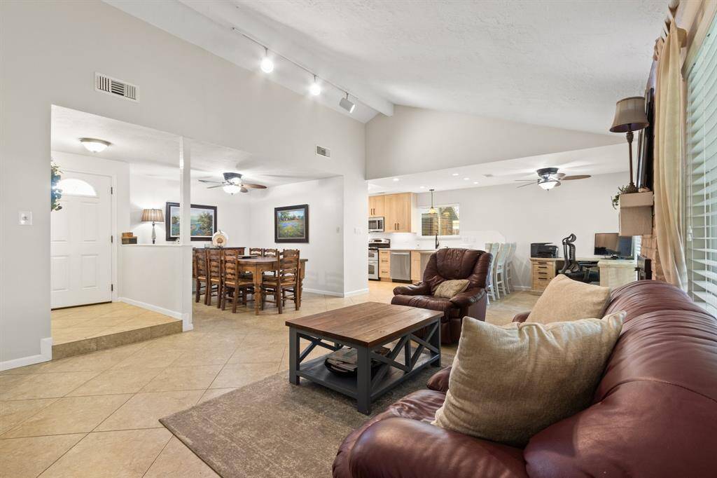 This inviting open-concept living area features a spacious dining area, and a modern kitchen with stainless steel appliances. High ceilings and neutral tones create a bright and airy atmosphere, perfect for relaxing and entertaining.