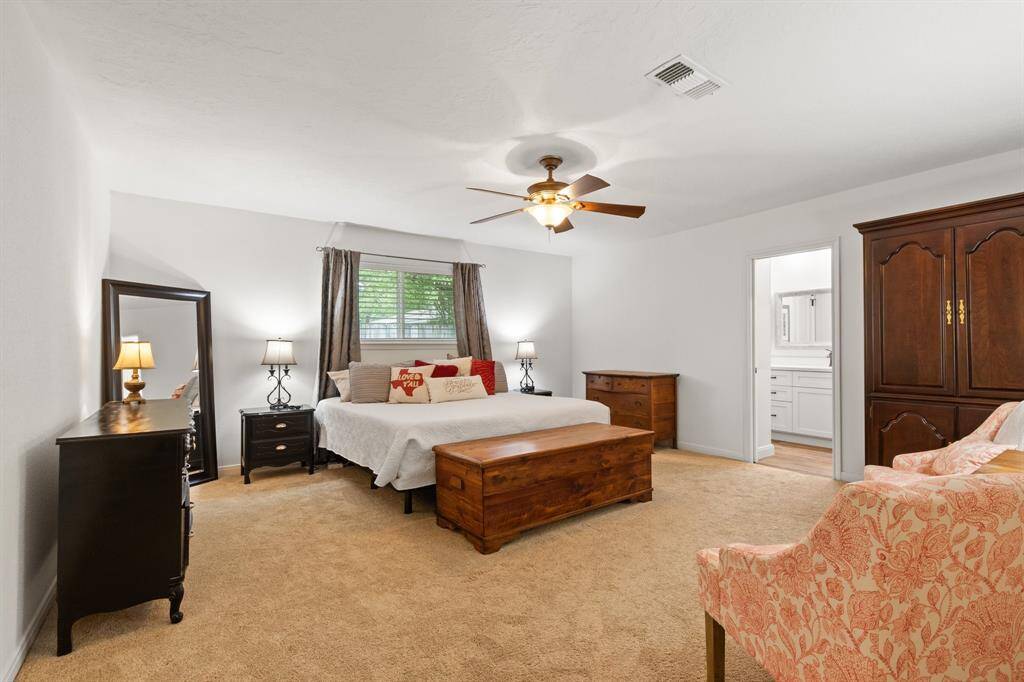 Spacious primary bedroom with neutral tones, featuring a large window, ceiling fan, and plush carpeting. This is a King sized bed, which shows how large this room is! The room also provides access to an ensuite bathroom, enhancing convenience and privacy.