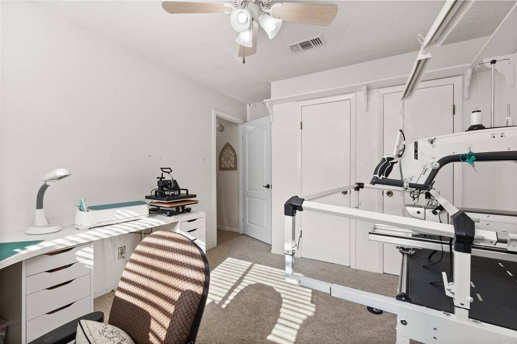 Bright and versatile room with a ceiling fan, ideal for crafting or as a home office. Features a large workspace, built-in storage, and carpeting for comfort.