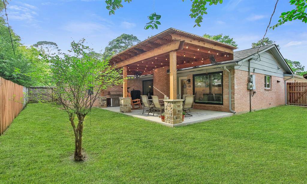 Charming backyard with a spacious patio featuring a wooden pergola perfect for outdoor entertaining. The well-maintained lawn and privacy fence create an inviting space for relaxation.