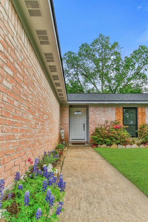 Charming brick exterior with a welcoming pathway leading to the front door. The garden features colorful flowers and well-maintained shrubs, enhancing curb appeal.