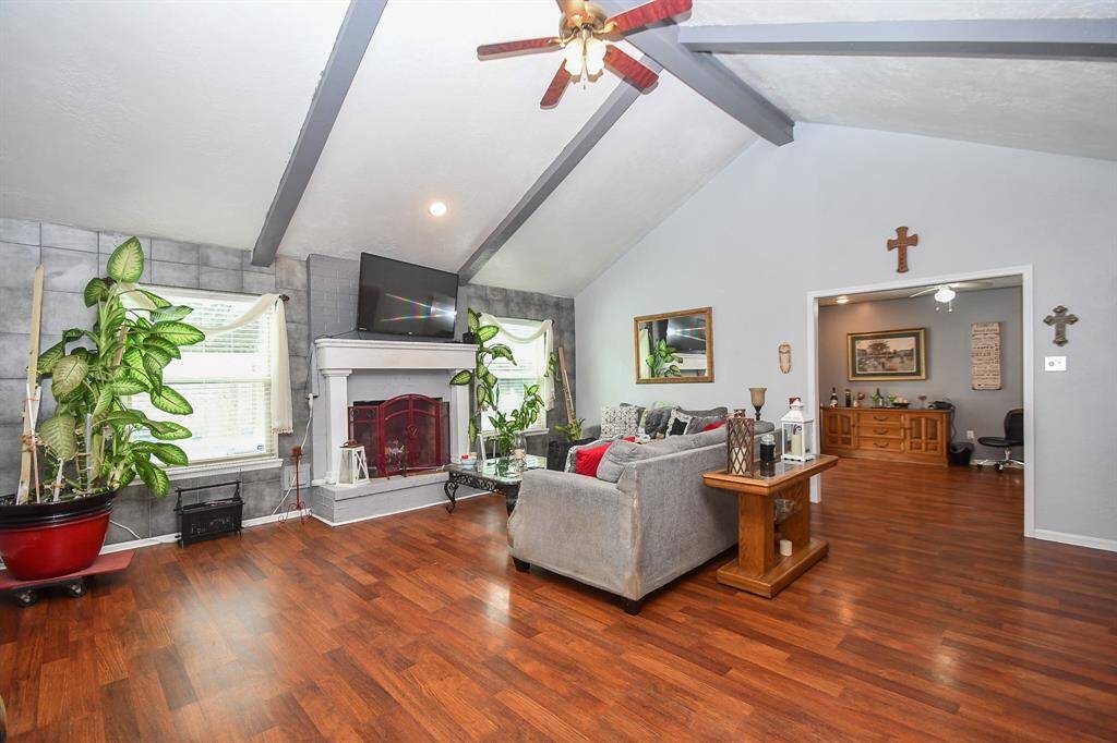 This is a spacious living area with vaulted ceilings, hardwood floors, a fireplace, and ample natural light. It includes modern finishes and a comfortable, inviting layout.