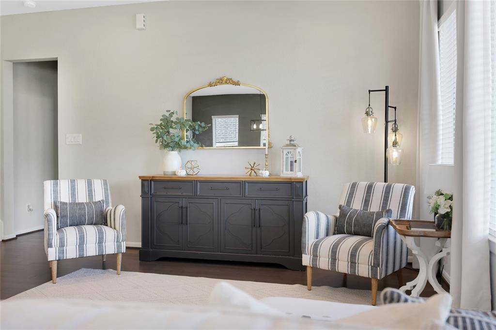 The principal bedroom features a neutral color palette with light grey walls that provide a warm ambiance. The space is well-lit by natural light from the side window.
