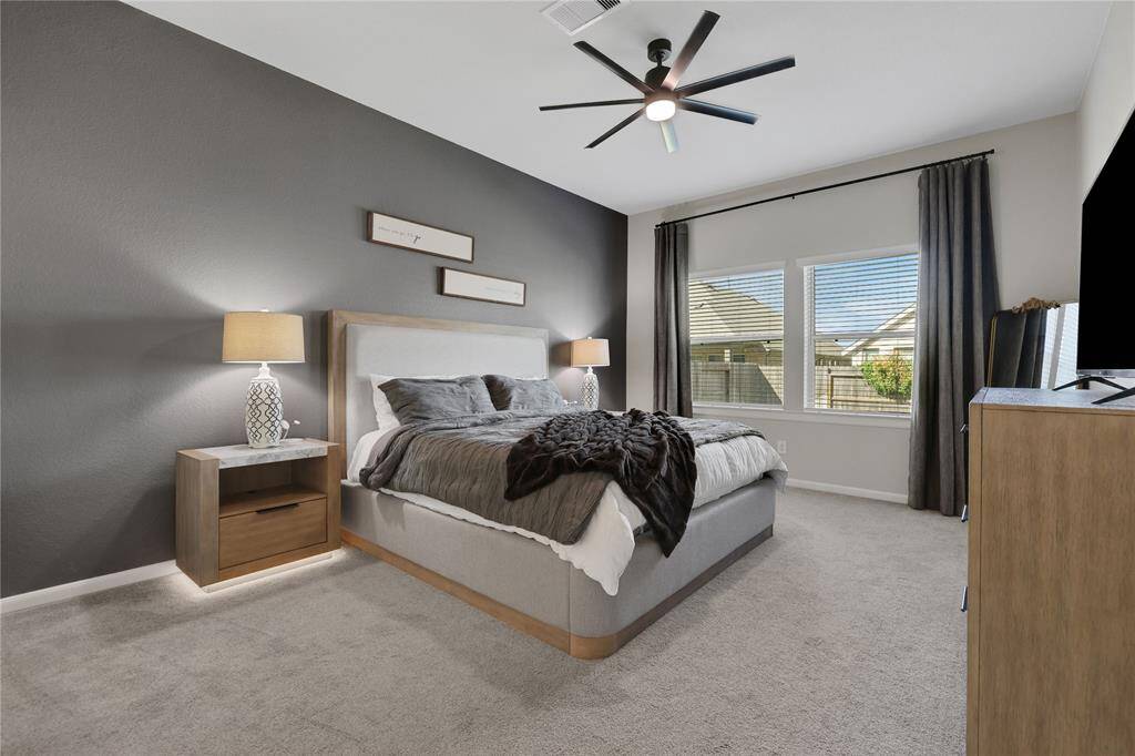 The large principal bedroom has a neutral color palette, with ample natural light from the window.