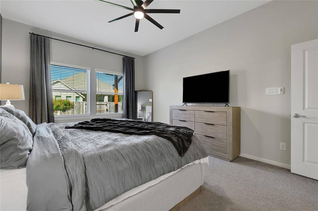 The principal bedroom with ample natural light, a neutral color palette, light carpet and high ceilings is perfect for relaxation.
