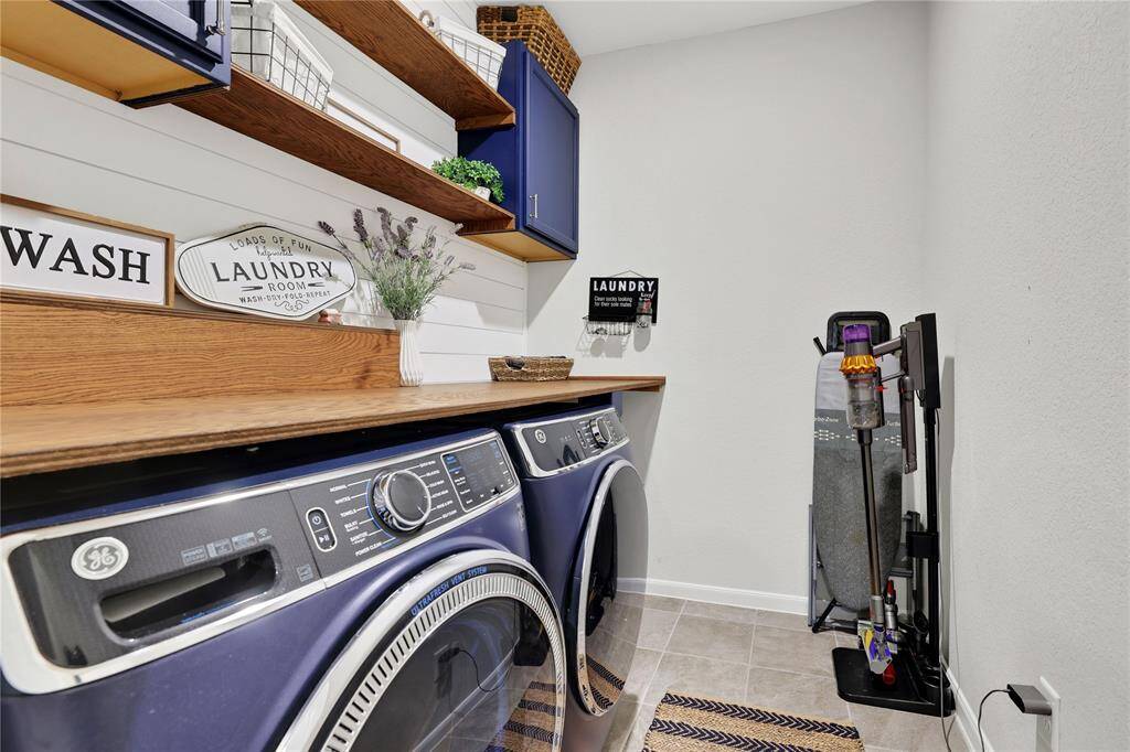 This is a tidy and well-organized laundry room featuring, wooden shelving for storage, and decorative touches that create a cozy atmosphere.