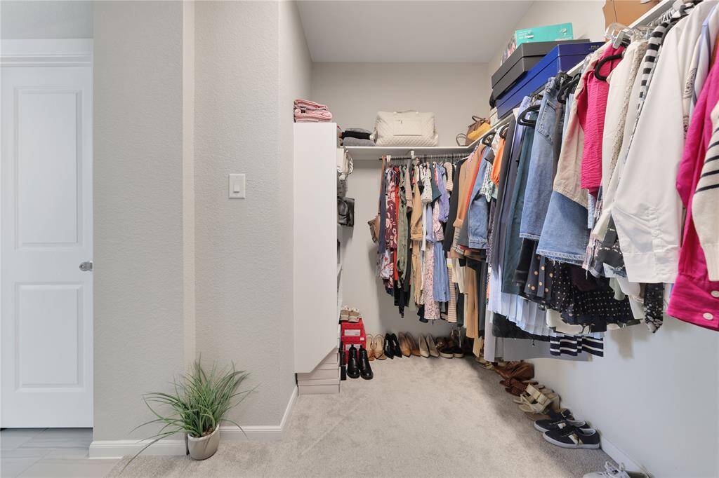 The walk-in closet features ample hanging space and storage for clothing and shoes, complemented by good lighting and neutral colors.
