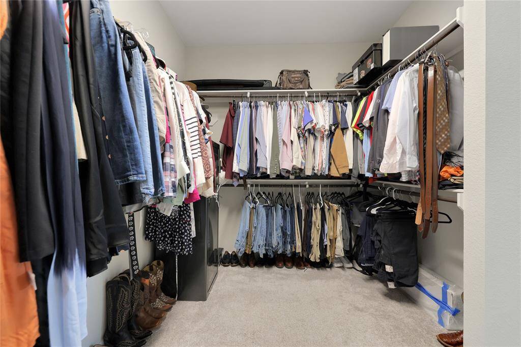 This is a well-organized, walk-in closet with ample hanging space and storage shelves, suitable for a variety of clothing and accessories.