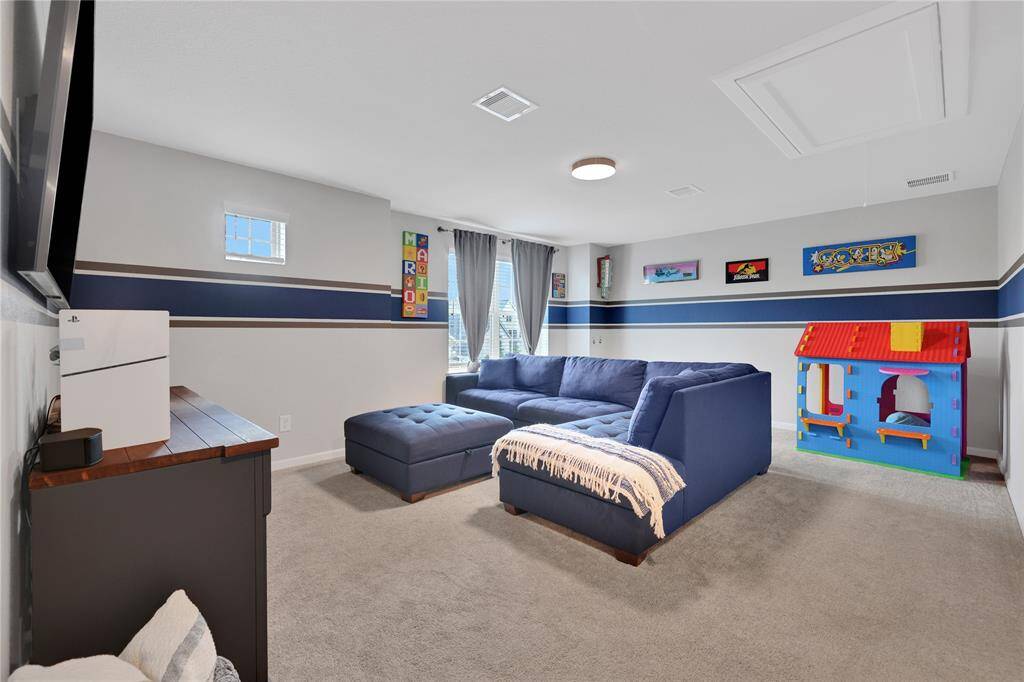 This is a cozy, well-lit game room on the second floor featuring tasteful decorative colors ideal for both relaxation and play.