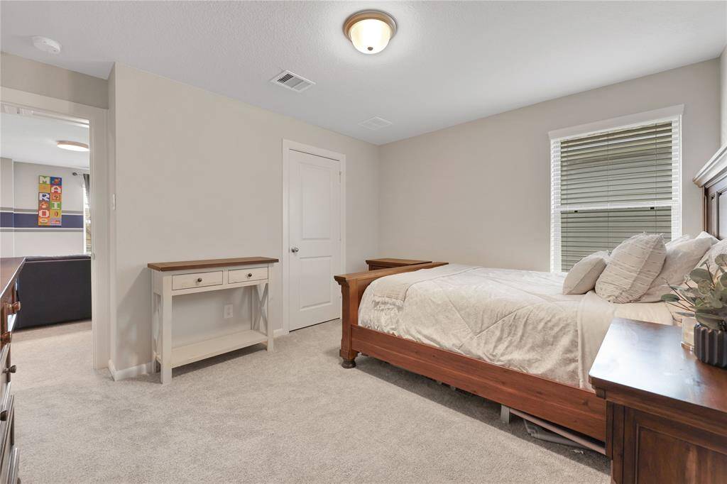 This is a well-kept, neutral-toned bedroom with carpet and good natural lighting on the second floor