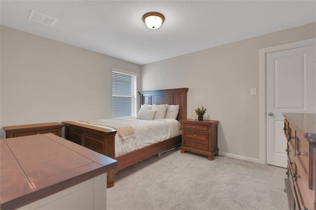 Another view of the second bedroom on the second floor with neutral wall colors, carpeted flooring, and is well-lit with a window