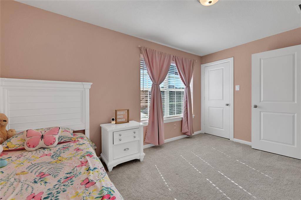 The third bedroom on the second floor features neutral carpeting, soft pink walls, white trim, and ample natural light.