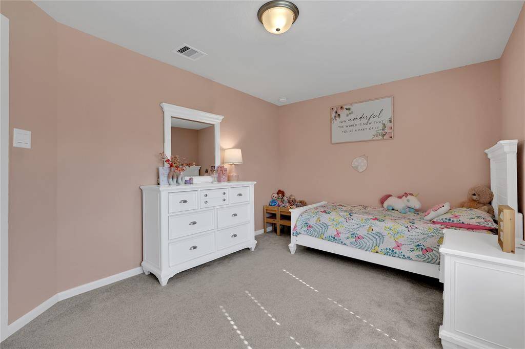 Another view of the well-lit bedroom featuring soft pink walls creates a warm and inviting space.