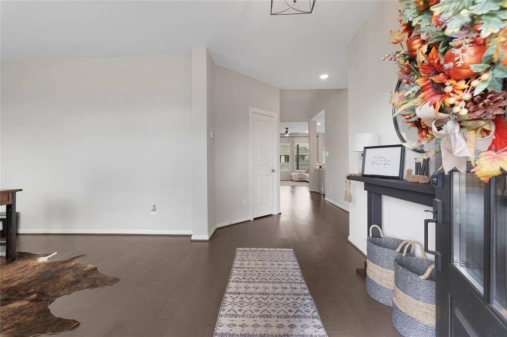 This is a bright and spacious interior with a contemporary design, featuring hardwood floors, a neutral color palette, and an open doorway leading to the home.
