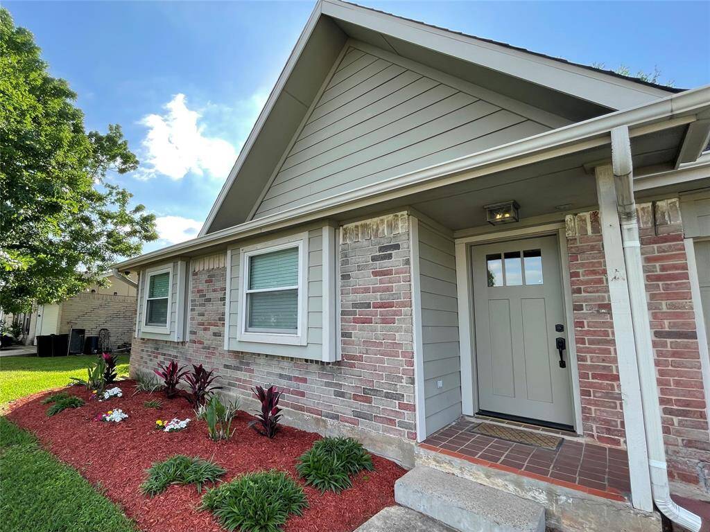 View of front porch and home's entry with views of the front flower bed.