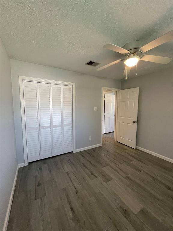 Secondary bedroom #1, located at the front corner of the home features a large closet with louvered doors and built-in shelving.