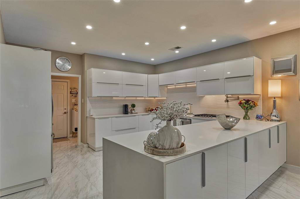 This newly remodeled culinary kitchen was reconfigured to enhance storage and entertaining space. Notice the sleek quartz waterfall countertops.