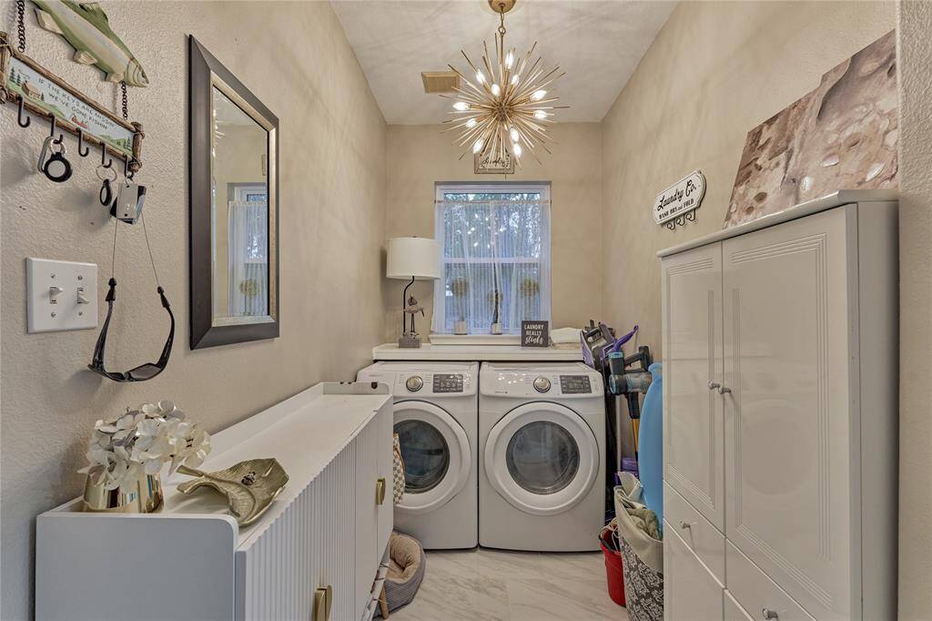 The laundry room features a built-in counter for folding clothes, ample storage and a fabulous statement chandelier.