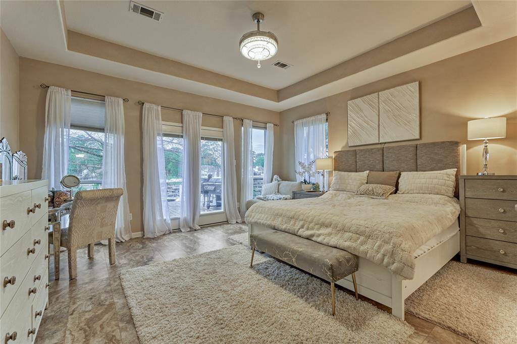 The primary suite features an elevated recessed ceiling and a wall-of-windows that let in tons of natural light and delightful serene water views.