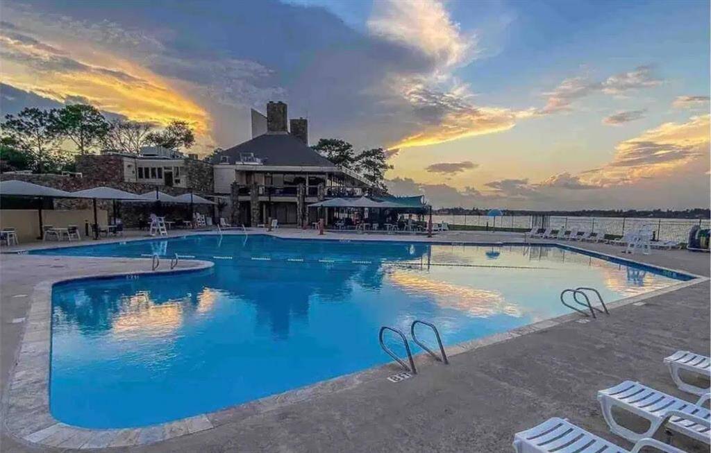 Resort-style pool with panoramic views of Lake Conroe, perfect for evening swims and sunset relaxation. Spacious deck area with lounge chairs and shaded seating, all just steps away from the water’s edge.