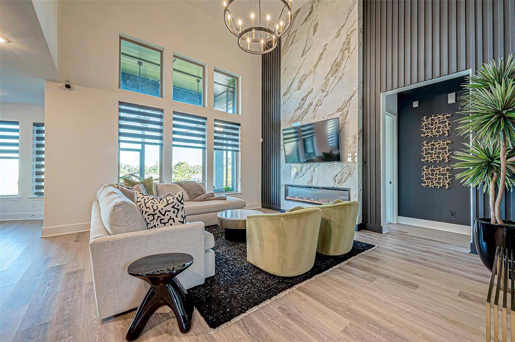 The spacious living area boasts soaring high ceilings that create an open and airy atmosphere, drawing the eye upward to a stunning chandelier that adds a touch of elegance and sophistication. The fireplace add charm and is perfect for relaxing evenings.