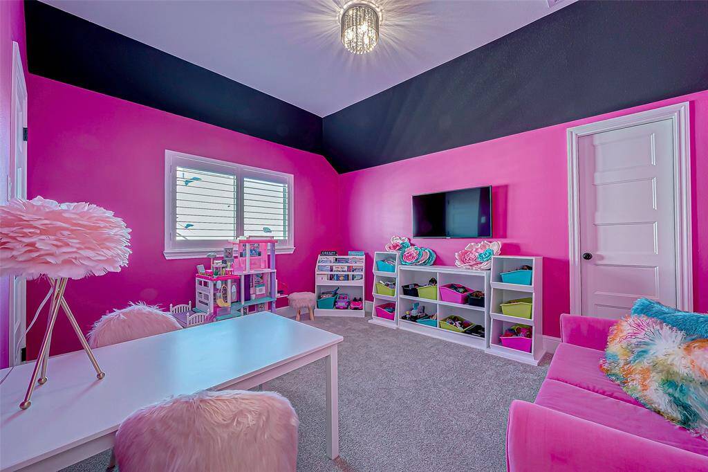 The vibrant secondary bedroom features an eye-catching design with bold bright pink and black walls, creating a striking contrast that adds personality and flair to the space. The room is full of character, offering a fun and energetic atmosphere, perfect for a teenager or a creative space.