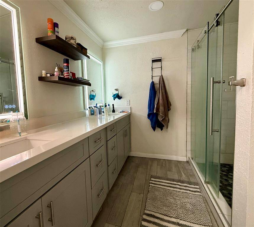 Completely remodeled bathroom with luxury vinyl flooring, new cabinets, quartz countertops, spacious shower, and LED anti-fog mirrors