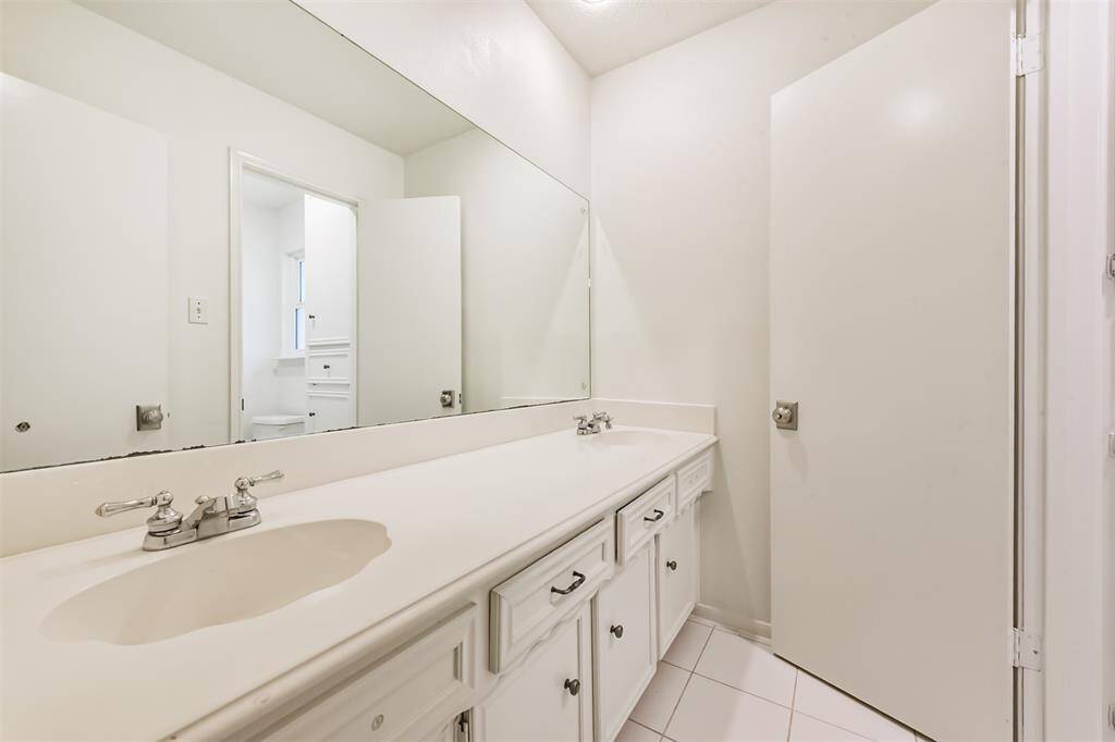 The second full bathroom features double sinks and tile floors.