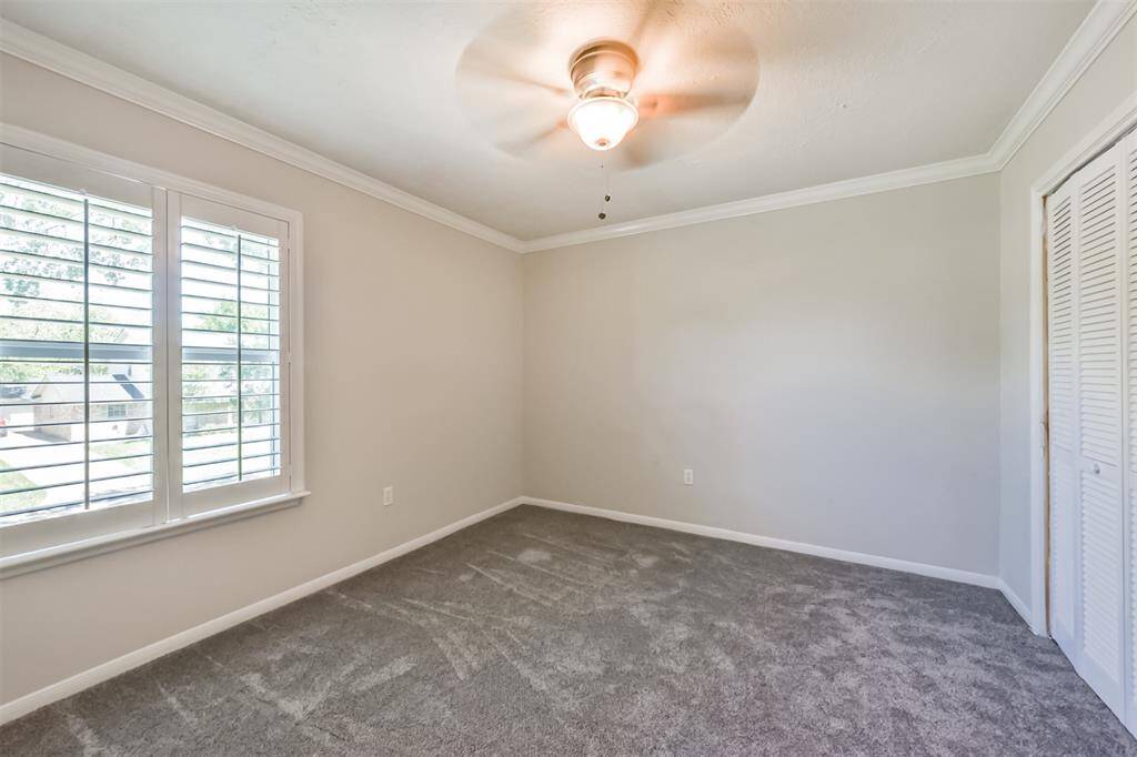 Bedroom #3 has recent carpet floors, crown molding, plantation shutters and a ceiling fan.