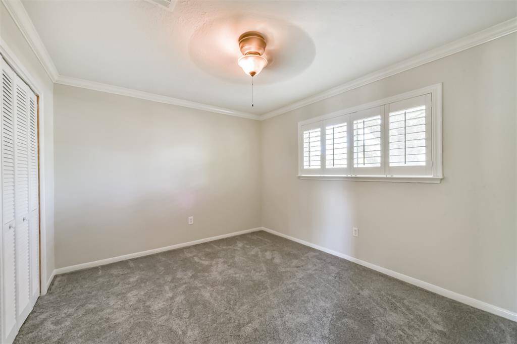 Bedroom #4 features crown molding, a ceiling fan and plantation shutters.