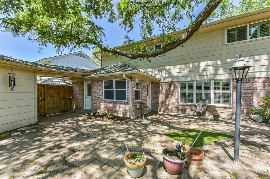 The backyard has a patio shaded by the mature trees.