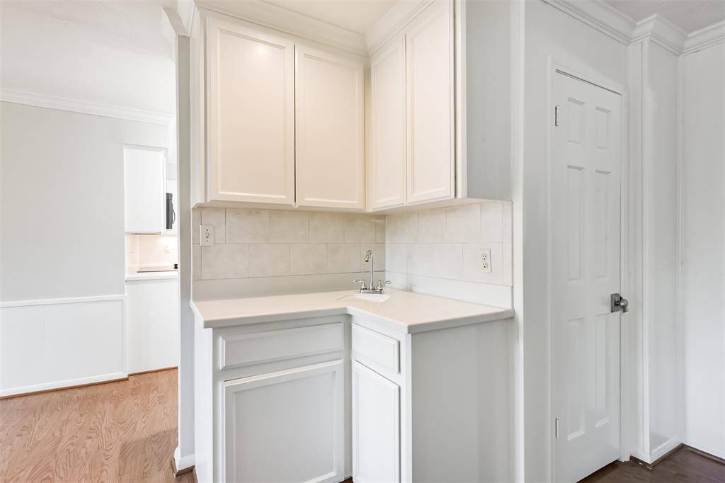 There is a wet bar with corian counters and tile backsplash.