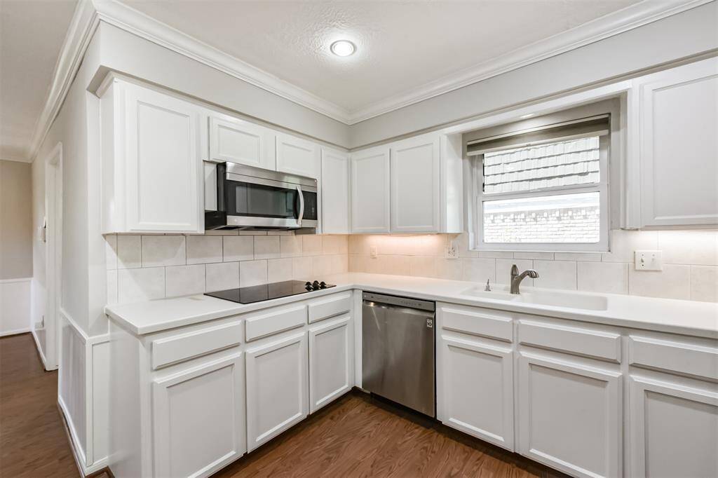 The kitchen features corian counters with tile backsplash, crown molding, SS appliances and recessed lighting.