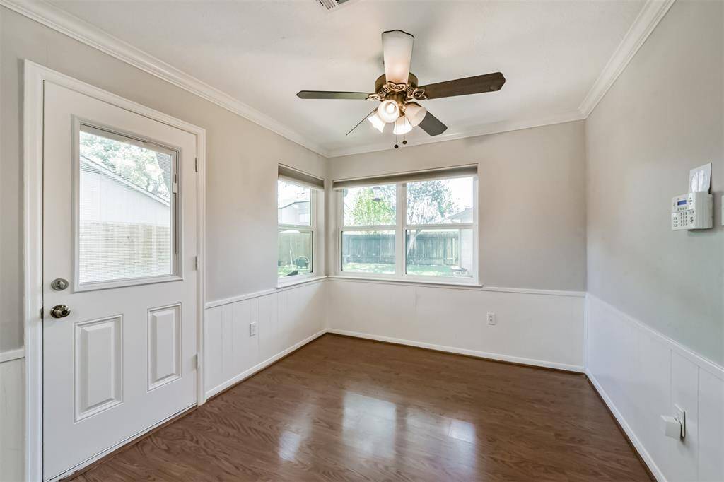 The breakfast area has crown molding, a ceiling fan and access to the backyard through the single door.