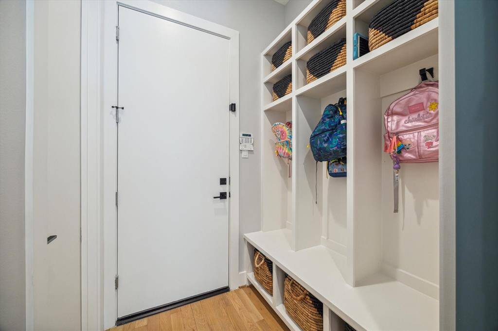 Adjacent to the kitchen, the mudroom provides great functionality. With its well-designed storage cubbies and hanging hooks, it's the perfect space to organize everyday essentials and keep clutter at bay. Door leads to an oversized 2-car garage with epoxy flooring and Elfa storage systems.