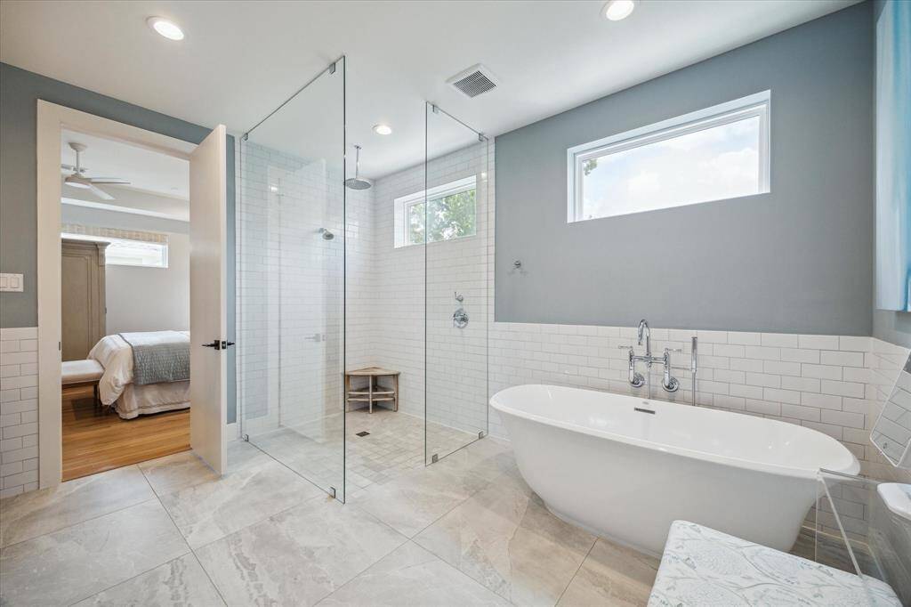 The luxurious primary bath offers a serene escape, featuring a deep soaking tub perfect for relaxation and a sleek glass-enclosed shower for a spa-like experience.