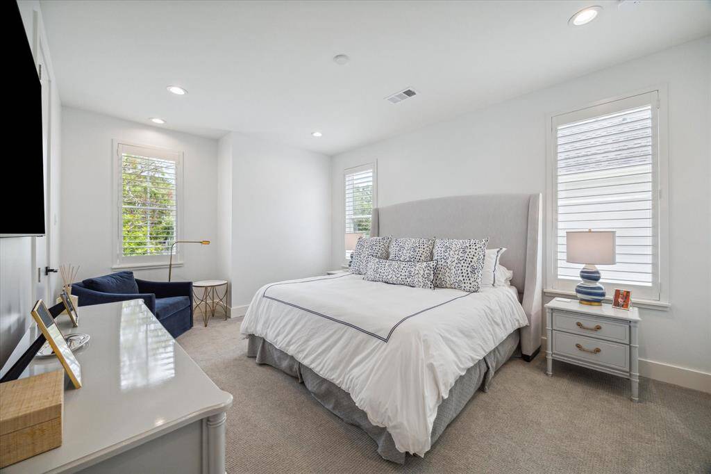 Bedroom #2 features plush carpet flooring, large windows with shutters, recessed lighting, and a full ensuite bath, offering both comfort and privacy.