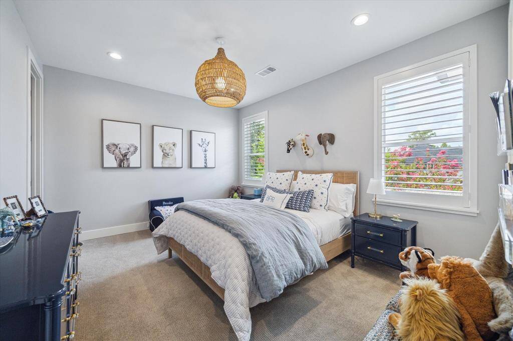 Bedroom #4 with carpet flooring, double windows with shutters, recessed lighting, updated rattan pendant light, and a large walk-in closet.