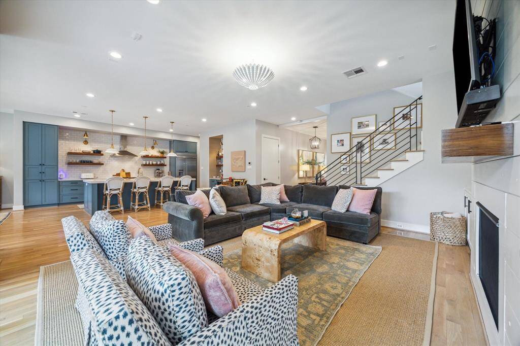 The room also features recessed lighting, and a designer chandelier with a sculpted metal leaf motif. The staircase with modern iron railing and custom New Zealand wool stair runner by Crescent, leads up to the bedrooms and game room.