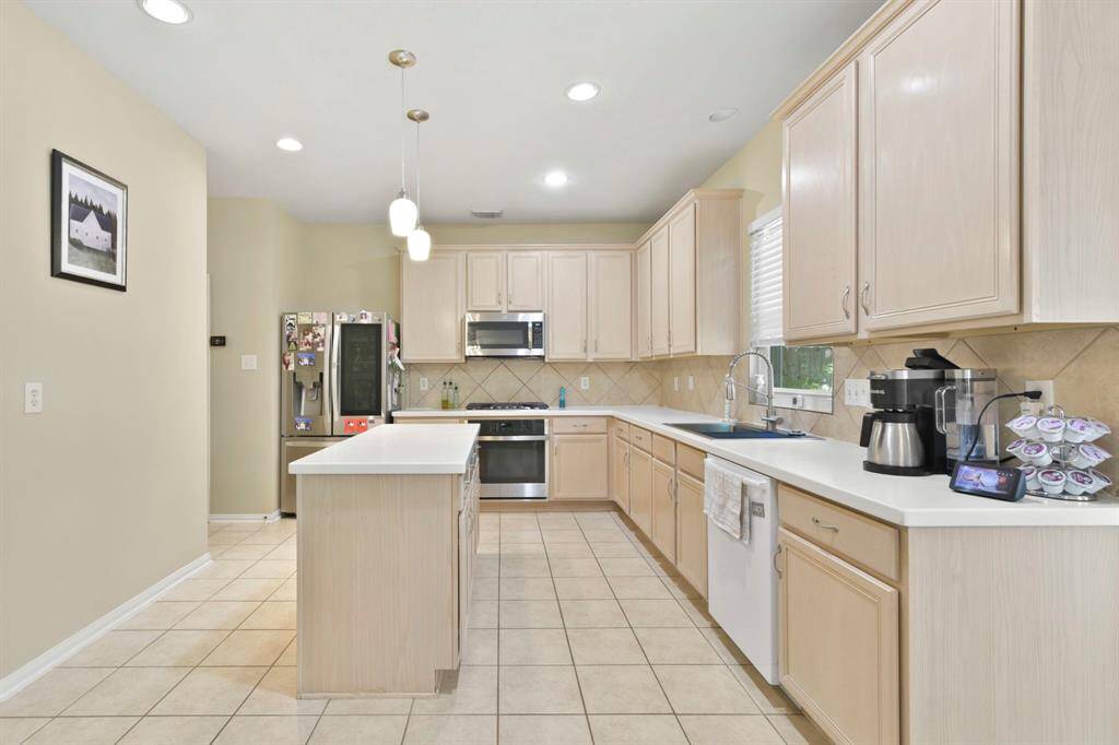 This view of the kitchen showcases the spacious island, offering both additional prep space and a convenient spot for casual seating. The light wood-look cabinetry and countertops create a cohesive, modern look, while the natural light highlights the open and inviting atmosphere. The island serves as the perfect centerpiece for both cooking and socializing, enhancing the kitchen’s functionality and style.