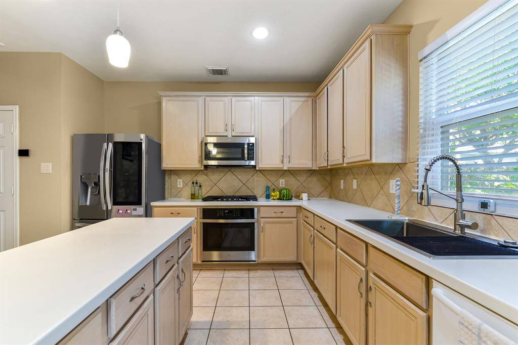 Stunning kitchen featuring sleek stainless steel appliances, a spacious island perfect for meal prep and entertaining, and beautiful ceramic tile flooring that adds a touch of elegance. This modern, functional space is ideal for creating delicious meals and making lasting memories.