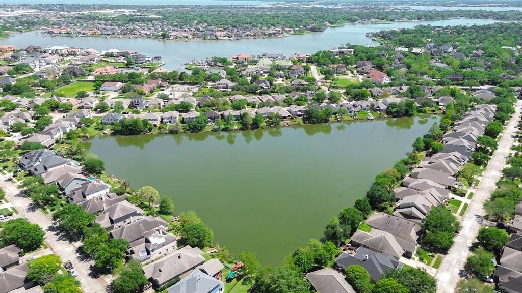 Take in a breathtaking full aerial view of the neighborhood lake, showcasing its tranquil waters and scenic surroundings. This expansive shot highlights the beauty of the lake and its natural landscape, offering a peaceful retreat right in the heart of the community. The expansive view offers a true sense of the serene environment and the stunning outdoor backdrop.