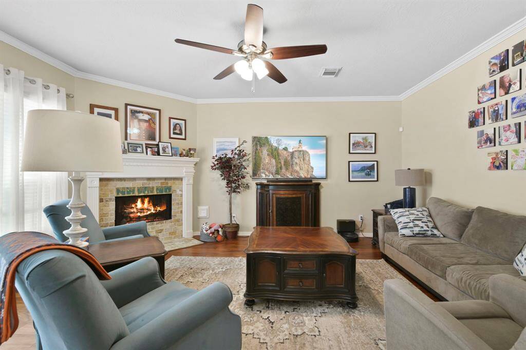 The living room features an abundance of natural light pouring in through large windows, creating a warm and inviting atmosphere. A cozy fireplace serves as the focal point of the space, perfect for relaxing evenings or gathering with friends and family. The neutral tones add to the serene, comfortable feel of the room.