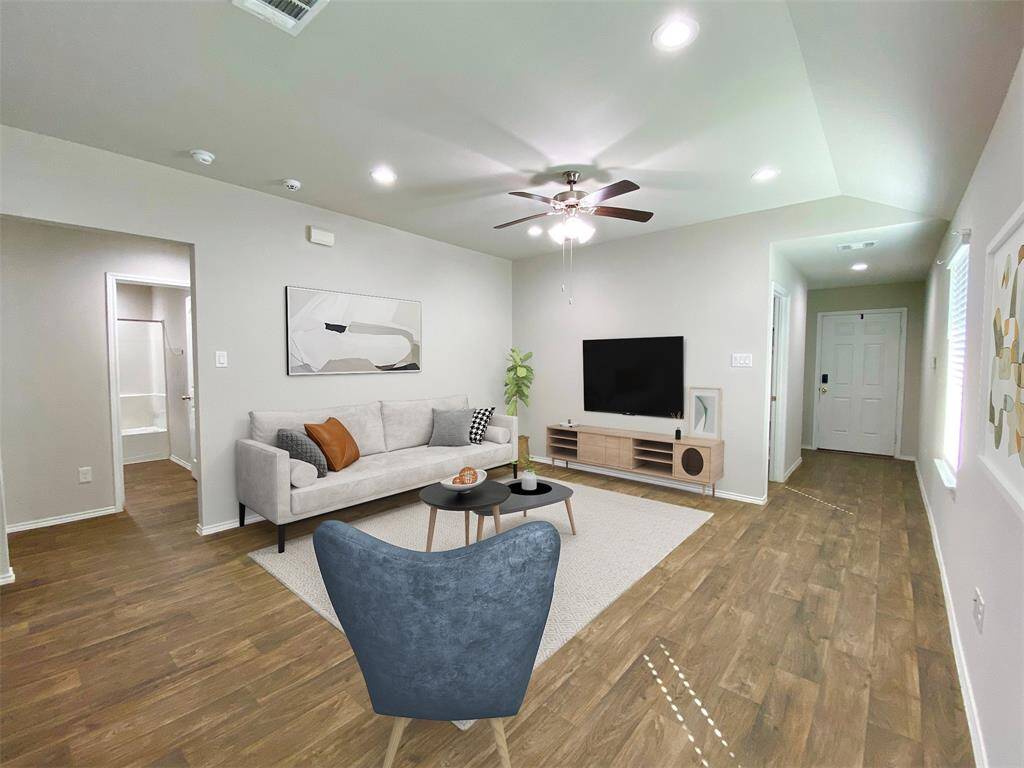 Bright and modern living room with vinyl plank flooring, neutral walls, and recessed lighting. Features room for sectional with breezy ceiling fan. Add your own touch of elegance.