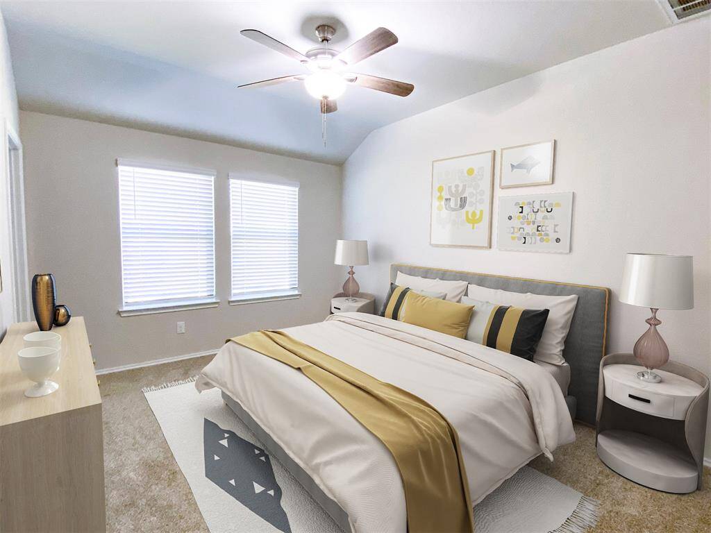 This bedroom is bright and inviting, featuring room for your comfortable bed with stylish bedding, two bedside tables with lamps, and a ceiling fan. Two large windows provide ample natural light, complementing the neutral ambiance.
